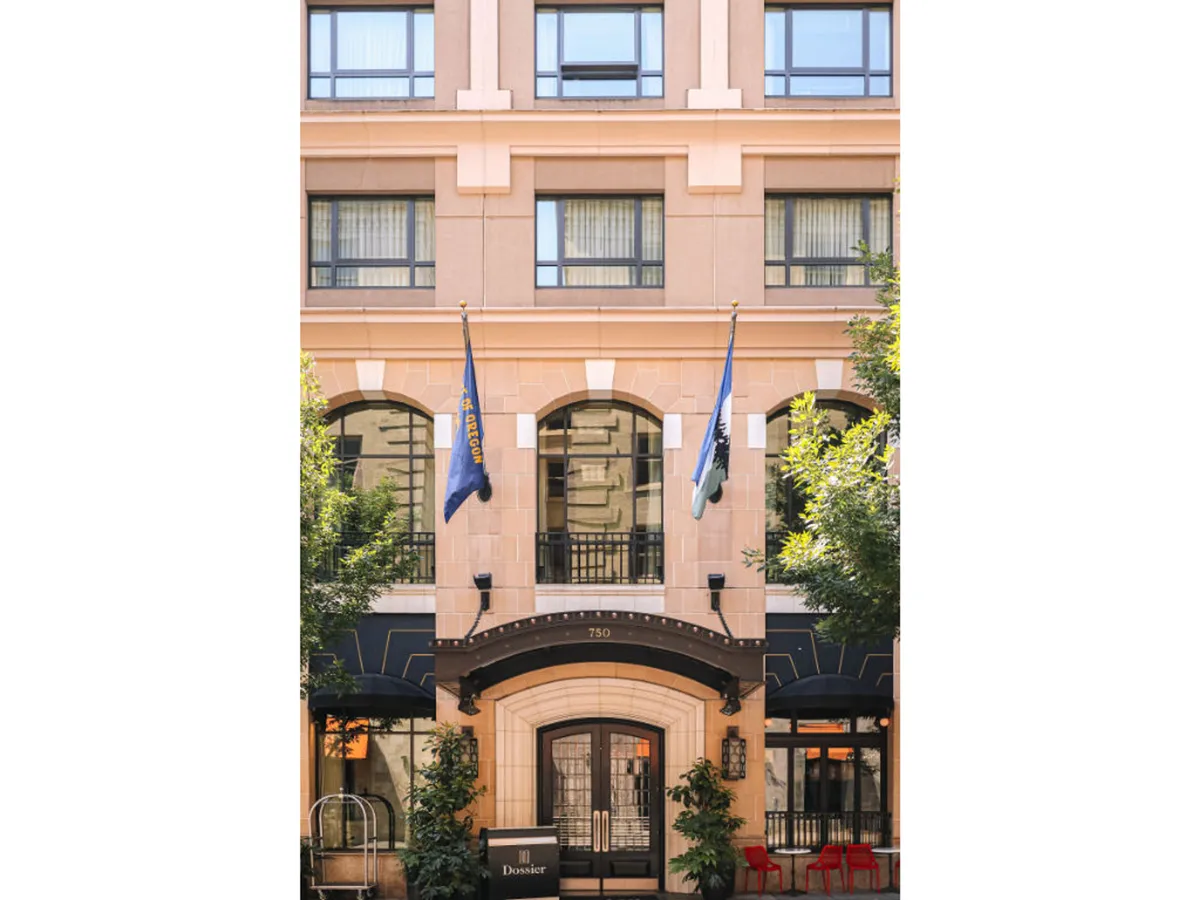 This exterior image captures the hotel’s entrance archway adorned with flags, large windows, and decorative architectural elements. The scene evokes a welcoming first impression and hints at easy access for all guests.